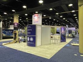 RENTAL: RE-9049 Island Design with Direct Print Sintra Graphics, Large Monitor Mount and 55" Monitor, Attached Tower Counter, and Client&acirc;��s Existing Reception Counter.