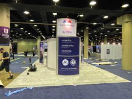 RENTAL: RE-9049 Island Design with Direct Print Sintra Graphics, Large Monitor Mount and 55" Monitor, Attached Tower Counter, and Client&acirc;��s Existing Reception Counter.